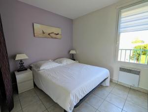 een slaapkamer met een wit bed en een raam bij Appartement avec vue sur golf in Pornic