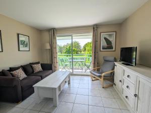 een woonkamer met een bank, een tv en een tafel bij Appartement avec vue sur golf in Pornic +8 foto's