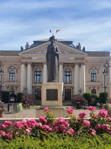 a statue in front of a building with pink flowers at Flowers in the Center in Oradea
