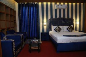 a hotel room with a bed and a chair at Hotel palm east lahore in Lahore