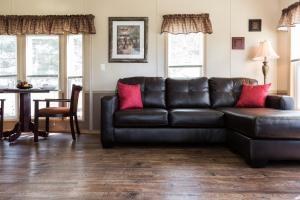 a black leather couch with red pillows in a living room at Red Shoes RV Park and Chalets in Kinder