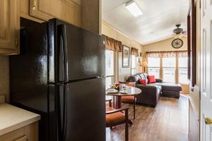 a kitchen with a refrigerator and a living room at Red Shoes RV Park and Chalets in Kinder