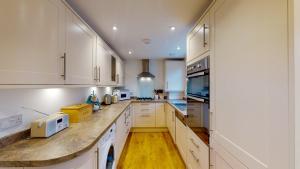 eine große Küche mit weißen Schränken und Holzböden in der Unterkunft Kingfisher Cottage in Sidmouth