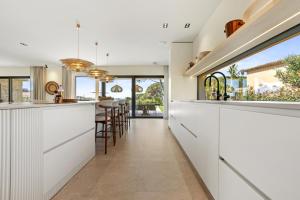 a kitchen with white cabinets and a bar with stools at Villa 400m² Vue mer proche centre in Sainte-Maxime