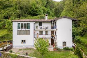 ein weißes Haus auf einem Hügel mit Bäumen in der Unterkunft la casa del borgo in Pulfero