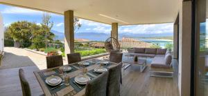 a patio with a table and chairs and a couch at PORTICCIO Maison vue mer in Porticcio