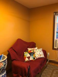 un sofá rojo con una almohada en una habitación en Room to stay in en South Ozone Park