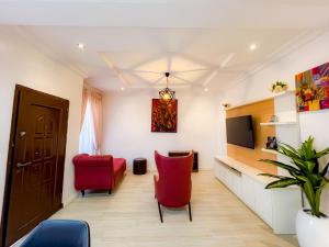 een woonkamer met rode stoelen en een televisie bij Box Residence in Lagos