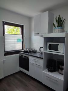 a white kitchen with a microwave and a stove at Ferienhaus Richard in Eschwege