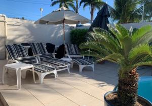 a group of chairs and an umbrella next to a pool at Sua Casa Francês in Marechal Deodoro