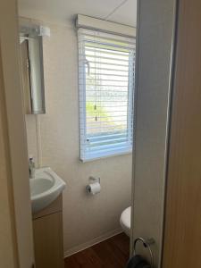 a bathroom with a sink and a toilet and a window at 21 Riverview, Allhallows in Rochester