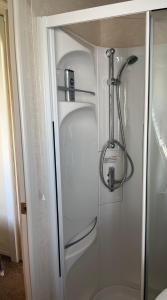 um frigorífico branco na casa de banho ao lado de um chuveiro em 21 Riverview, Allhallows em Rochester