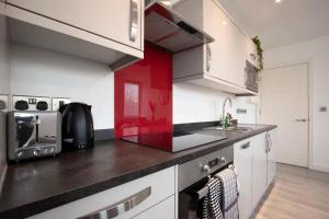 una cucina con armadietti bianchi e parete rossa di Central Gloucester Getaway Retreat W/Free Parking 