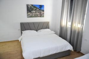 Schlafzimmer mit einem Bett mit weißer Bettwäsche in der Unterkunft Hotel Villa Edis in Berat