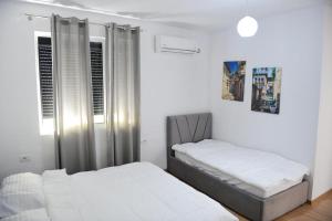 two beds in a bedroom with white walls at Hotel Villa Edis in Berat
