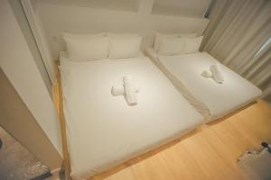 two beds in a small room with white sheets at Double H Boutique Hotel in Kuala Terengganu