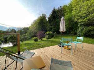 eine Terrasse mit einem Tisch, einem Sonnenschirm und Stühlen in der Unterkunft Moho Nat’ure Tiny-house in Saint-Nabord