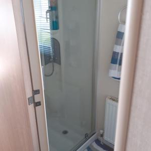 ニューキーにあるSuperb position 2 bedroom Caravan Newquay Walesのガラスドア付きのシャワー付きのバスルーム