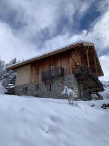 a wooden cabin with a balcony in the snow at Chalet Les Ecrins in Villard-Reculas
