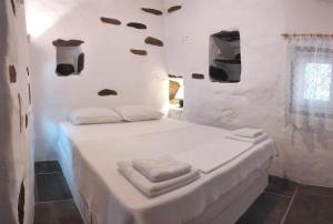 Habitación blanca con cama y toallas. en Fyrou- Serenity / Idyllic Traditional Experience, en Artemonas