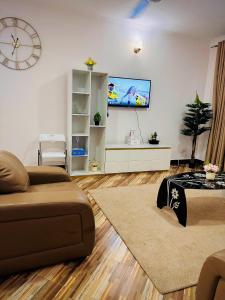 uma sala de estar com um sofá e uma televisão de ecrã plano em treasury em Bagamoyo
