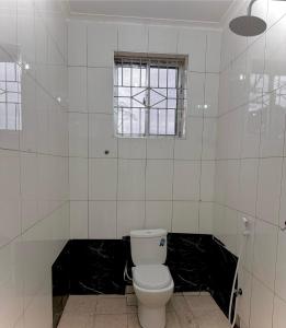a white bathroom with a toilet and a window at treasury in Bagamoyo