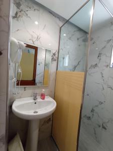 y baño con lavabo, espejo y ducha. en Achilles Apartments, en Sarandë