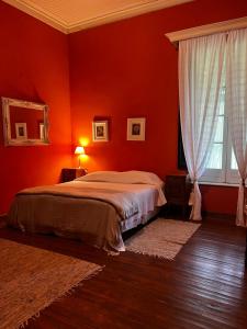 Dormitorio rojo con cama y ventana en Estancia La violeta en Chajarí