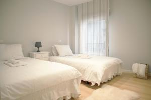 ein weißes Schlafzimmer mit zwei Betten und einem Fenster in der Unterkunft Apartamento en Ribeira in Ribeira