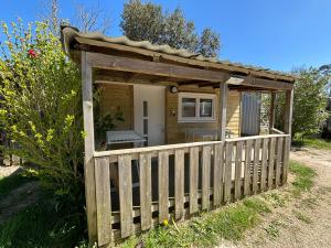 a wooden cabin with a fence in a yard at Camping Le Repos in Saint-Palais-sur-Mer
