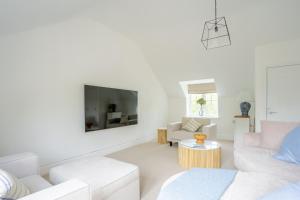 a living room with white furniture and a flat screen tv at York Cottage in Whitby