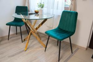 twee groene stoelen en een glazen tafel in een kamer bij Casa Alis in Oradea