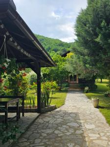 a walkway with a table and a bench in a garden at Holiday House Bella in Bihać