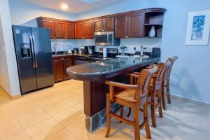 a kitchen with a large counter with chairs and a refrigerator at Stylish 3-BR Vacation Condo with Scenic Rooftop in Jacó