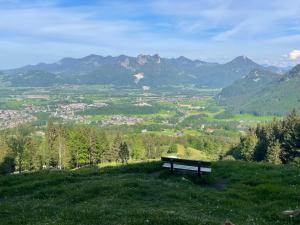 a bench sitting on top of a hill overlooking a valley at Ferienwohnung Alpenblick in Bruckmühl