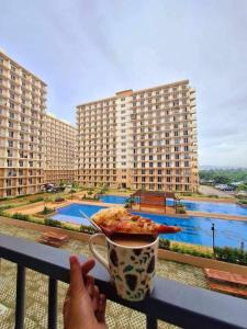 a person holding a plate of pizza and a cup of coffee at MaryneL Suites in Suba