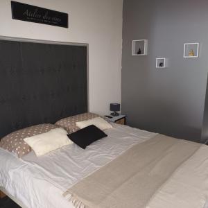 een groot bed met een zwart hoofdeinde en witte kussens bij Chez Nous in Le Rove