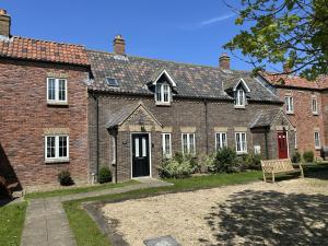 a brick house with a bench in front of it at Life of Filey - Part of the The Bay Filey Holiday Village with pool, gym and direct beach access, pub, restaurant, tennis and meadows walks in Reighton