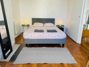 a bedroom with a bed with two tables and two rugs at Charming & cocooning flat - Canal de l’Ourq in Pantin
