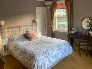 een slaapkamer met een bed, een bureau en een raam bij Holly House in Ebrington
