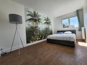 ein Schlafzimmer mit einem Bett und einem Palmenmilch in der Unterkunft Grand appartement 3 chambres Disney - Paris - 82m2 in Neuilly-sur-Marne