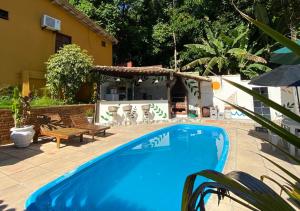 a blue swimming pool in a yard with a house at Pousada Alto da Praia in Arraial d'Ajuda