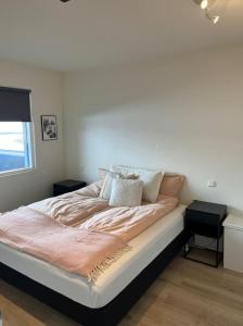 ein großes Bett in einem Zimmer mit Fenster in der Unterkunft Two bedroom family apartment in Akureyri