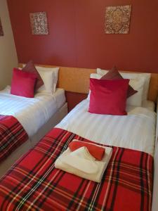 2 camas con almohadas rojas y bandeja. en Cosy Woodlands Lodge with Hot Tub, Decking & Garden, en Beattock