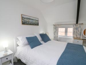 ein Schlafzimmer mit einem weißen Bett mit blauen Kissen in der Unterkunft 1 Penporth in Rhayader
