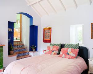 um quarto com uma cama grande e almofadas coloridas em Casa da Encosta - Hillside cabin near the sea em Colares