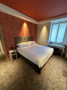 a bedroom with a large white bed and two windows at H&ocirc;tel Le M&eacute;di&eacute;val Palais des Papes in Avignon