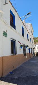 un edificio blanco con ventanas azules y una calle en Xenia Alojamientos, en Santiago de la Espada