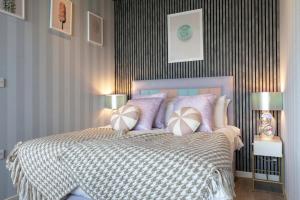a bedroom with a bed with purple and white pillows at Palm Tree House - Candyland in Orpington