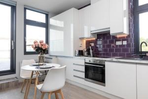 a kitchen with white cabinets and a table and chairs at Palm Tree House - Candyland in Orpington